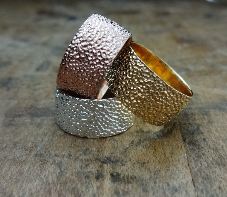 Simple elegant broad ring bands hand textured to emulate the dappled light naturally found in nature handmade in NYC by designer Jayne Moore model Jayne Moore from recycled refined metals in 18kt gold a light classic timeless wedding band for him or for her 